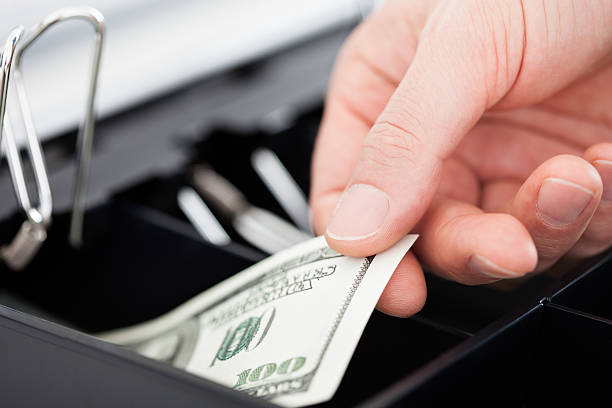 Close-up Of Hand With Dollar Notes Over Container